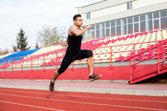 male athlete running on racing track at stadium